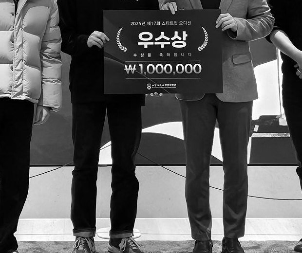 People on a stage, shown from the shoulders down, holding an award board reading 우수상, ₩1,000,000.